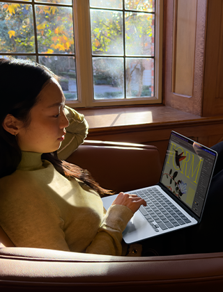 บุคคลหนึ่งนั่งอยู่บนเก้าอี้และกำลังใช้ MacBook Air